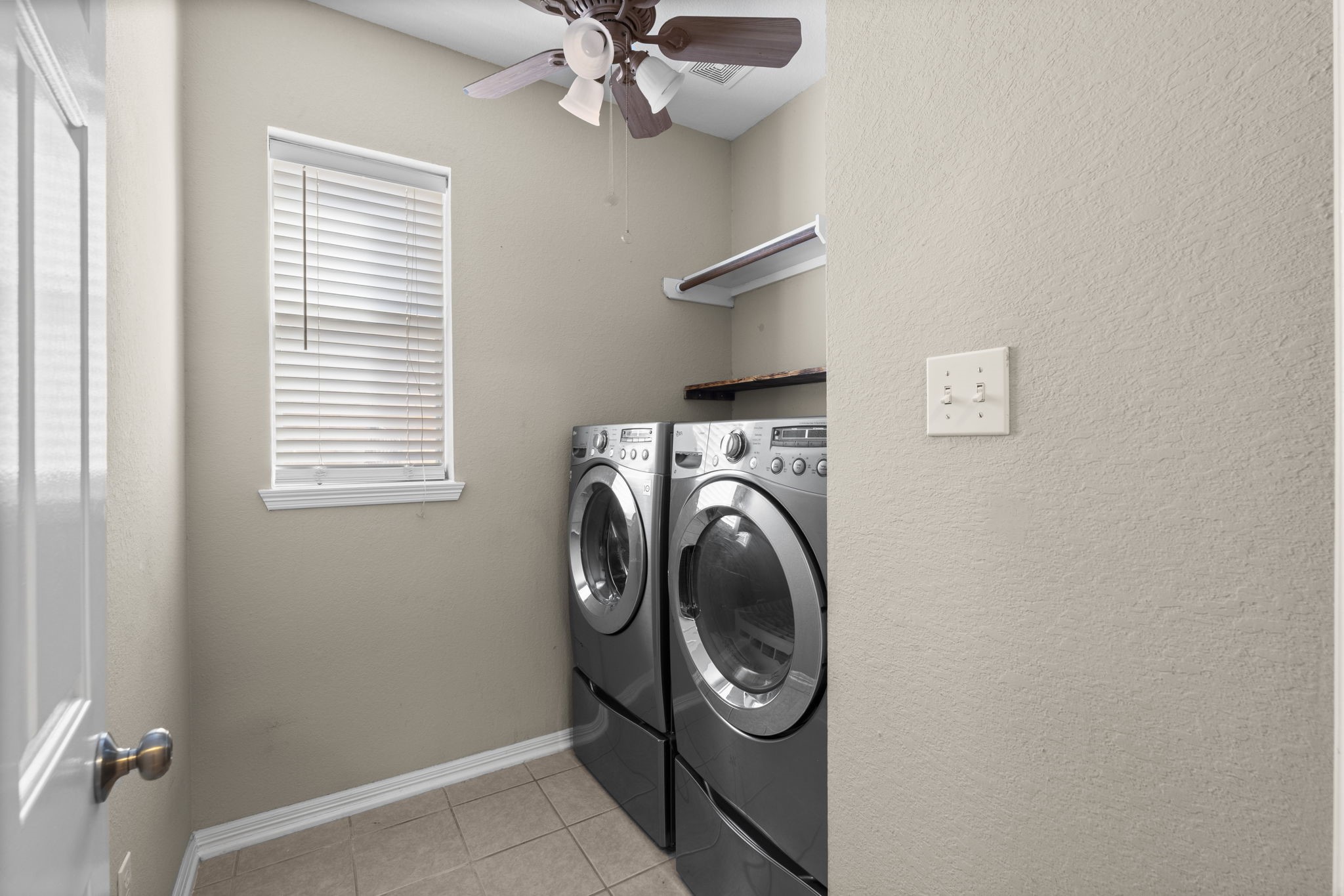 19327 Dickson Park Drive Spring, TX 77373 - Photo 22 of 43 The washer and dryer stay in this fabulous laundry room featuring tile flooring, shelving for storage, a sunny window with blinds, and lighted ceiling fan.
