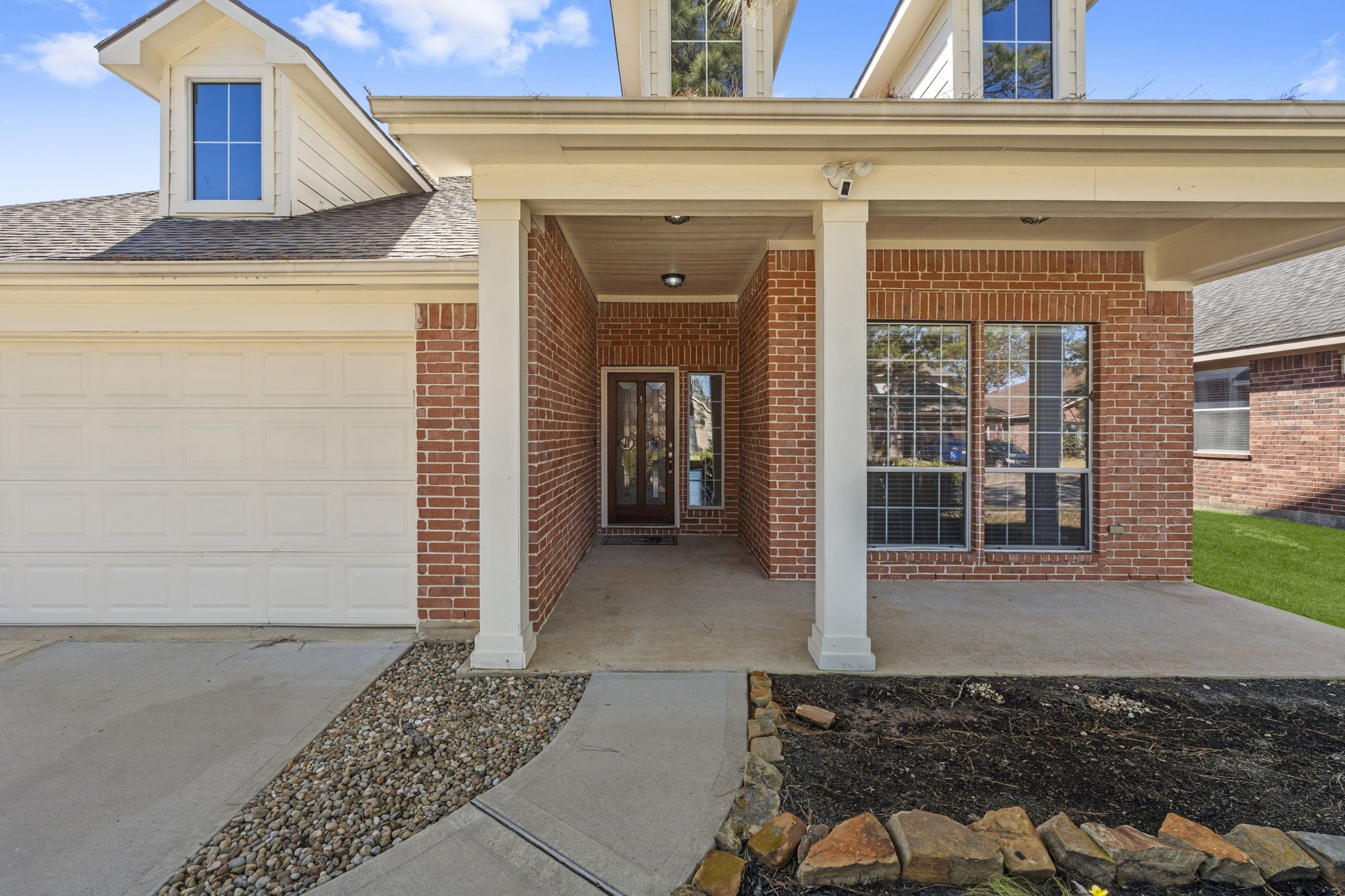 19327 Dickson Park Drive Spring, TX 77373 - Photo 3 of 43 The exterior showcases exquisite architectural detail, highlighted by stately columns and charming dormer windows that create striking curb appeal. A welcoming front porch adds a touch of Southern charm and whimsical elegance. The grand mahogany wood entry door with leaded glass and huge sidelight makes a statement all its own.