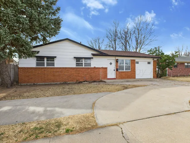 a view of a house with a yard covered with large trees