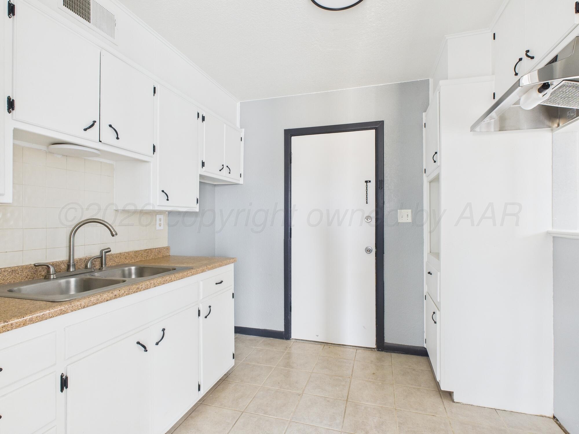 1002 Northeast 4th Street Dumas, TX 79029 - Photo 3 of 8 a kitchen with a sink and a refrigerator