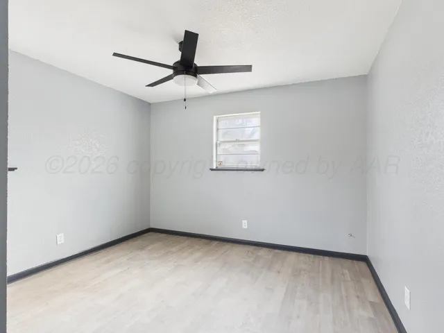 an empty room with a window and a fan