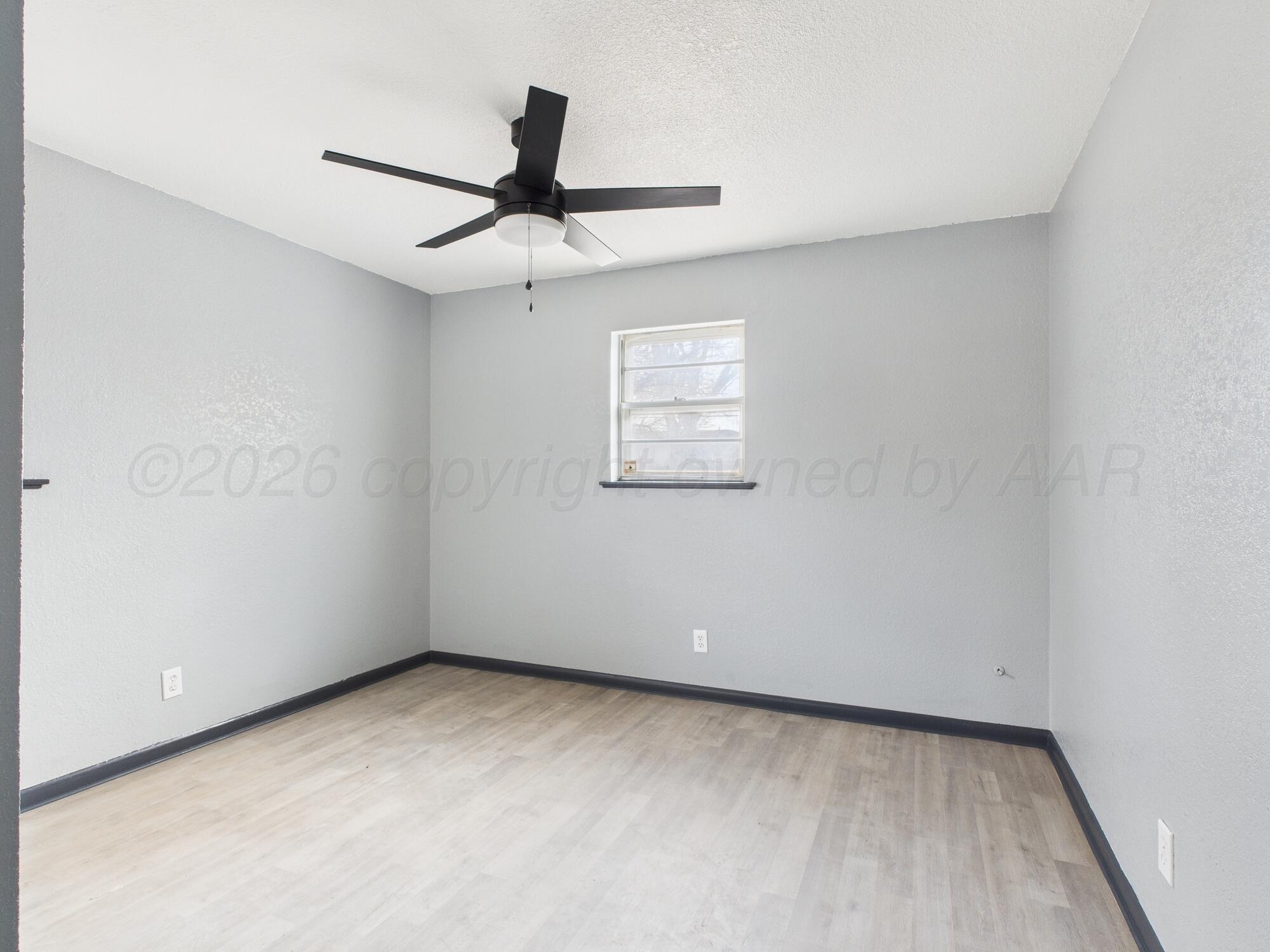 1002 Northeast 4th Street Dumas, TX 79029 - Photo 6 of 8 an empty room with a window and a fan