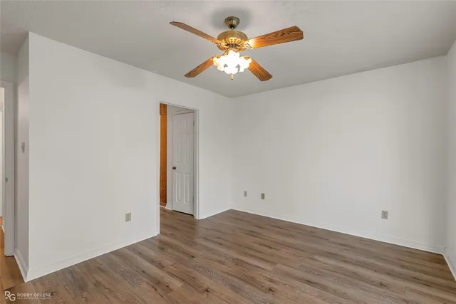 an empty room with wooden floor and a ceiling fan