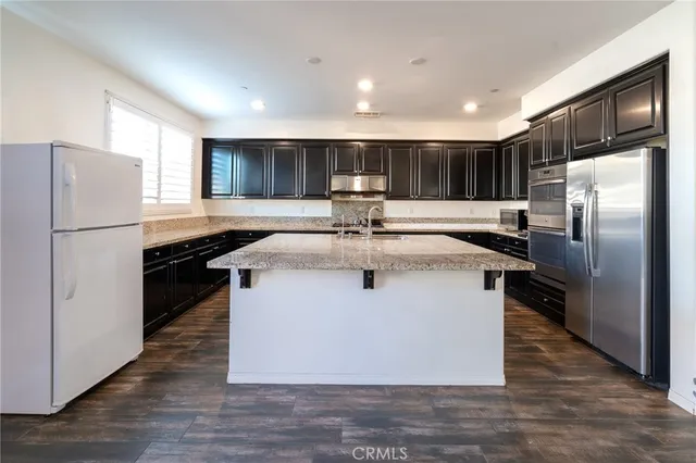 a kitchen with kitchen island a refrigerator and a sink