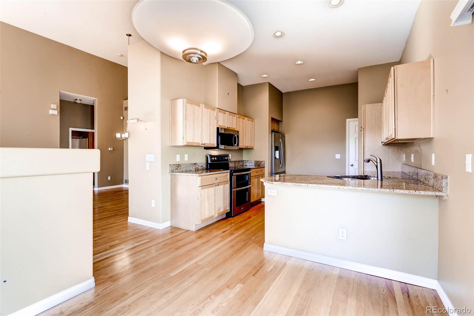 8300 Fairmount Drive, Unit N101 Denver, CO 80247 - Photo 14 of 27 a kitchen with granite countertop a refrigerator and a stove top oven