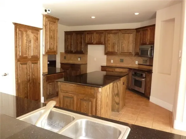 a kitchen with kitchen island granite countertop a sink a stove and refrigerator