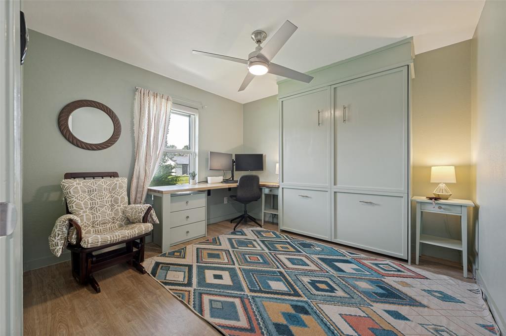3619 Merrell Road Dallas, TX 75229 - Photo 18 of 26 Room featuring wood-finish flooring, a ceiling fan with integrated lighting, a built-in desk with cabinetry, a window with natural light, and a built-in wall unit