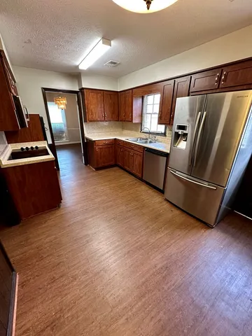 a kitchen with stainless steel appliances kitchen island granite countertop a refrigerator and a stove
