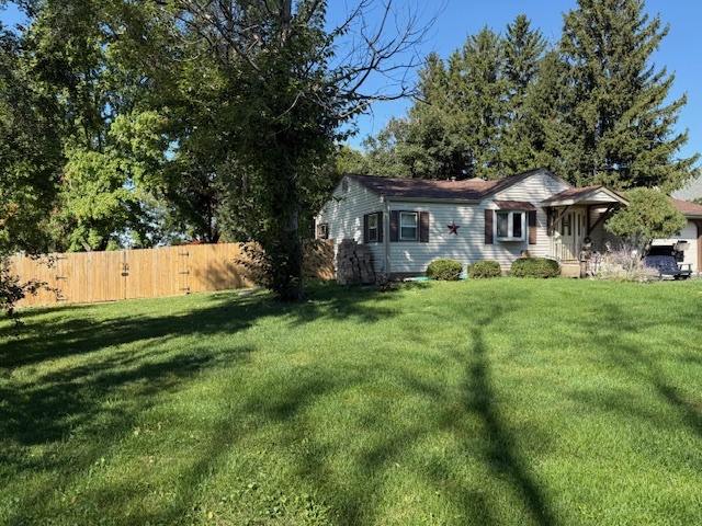 a view of a house with a big yard and potted plants and large trees