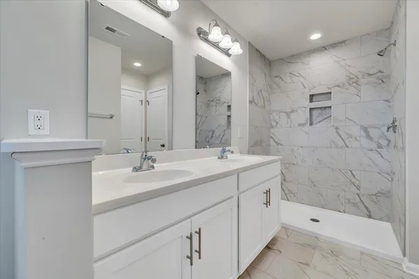 a bathroom with a double vanity sink mirror and shower