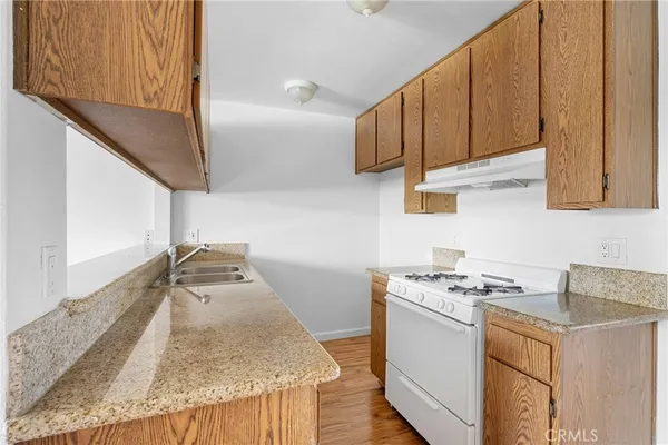 a kitchen with granite countertop a sink stove and cabinets