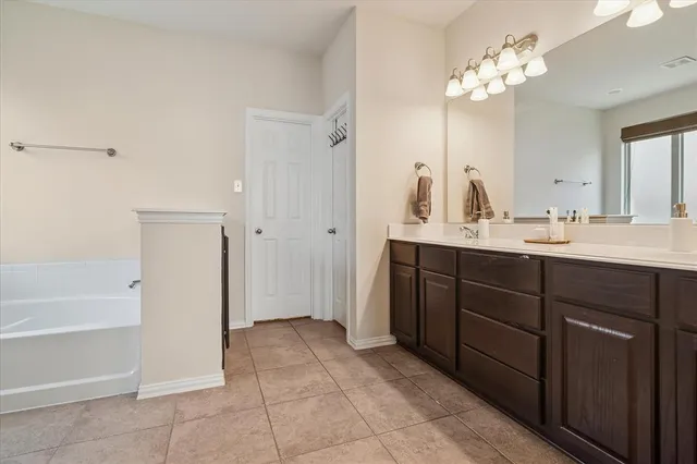 a spacious bathroom with a double vanity sink a mirror a bathtub and a shower