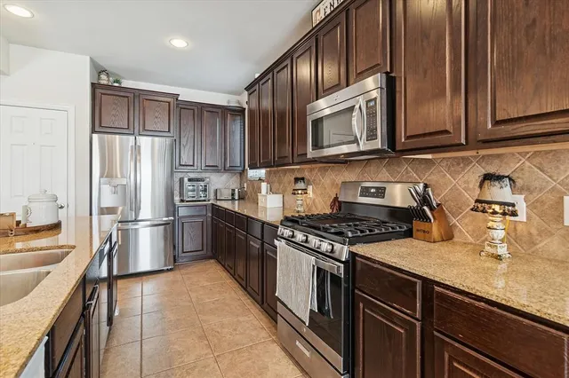 a kitchen with stainless steel appliances granite countertop a refrigerator stove and sink