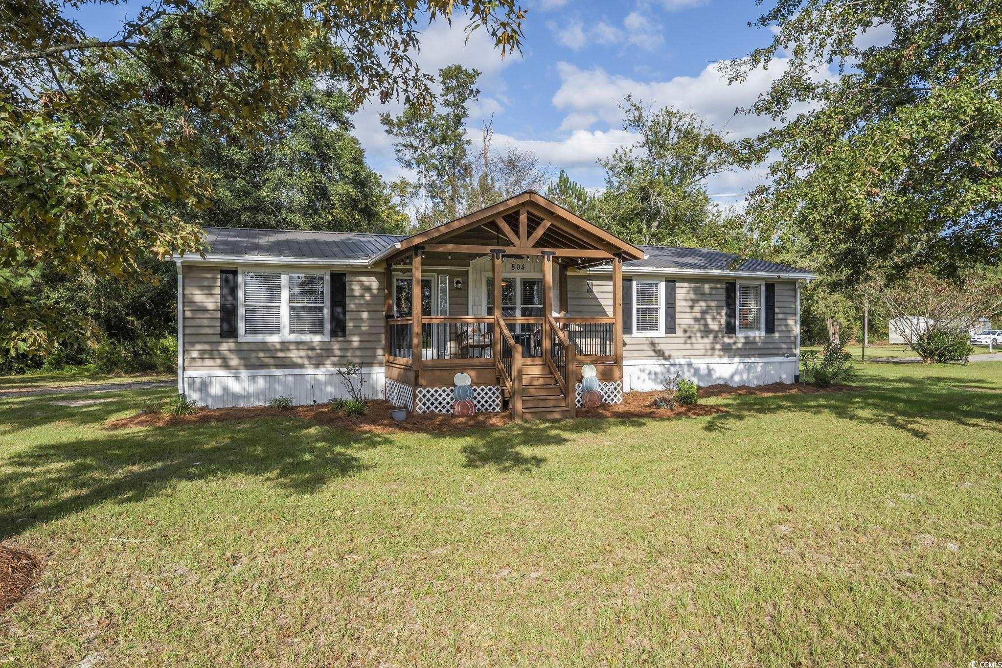 View of front of home featuring a front lawn and a wooden deck