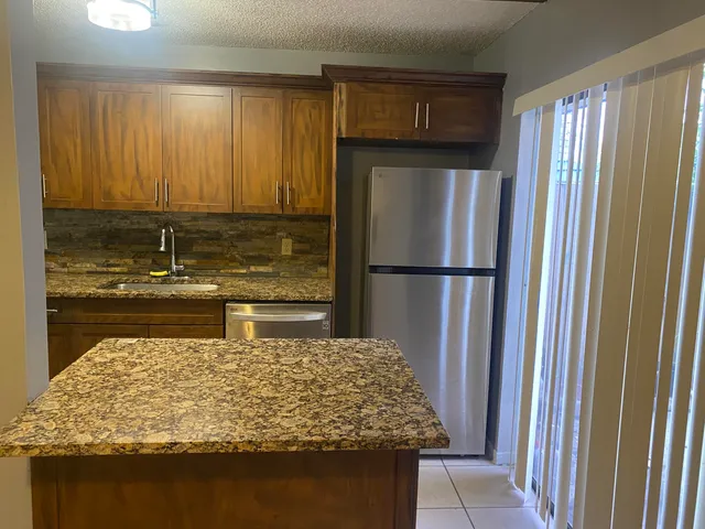 a kitchen with kitchen island a refrigerator and a sink