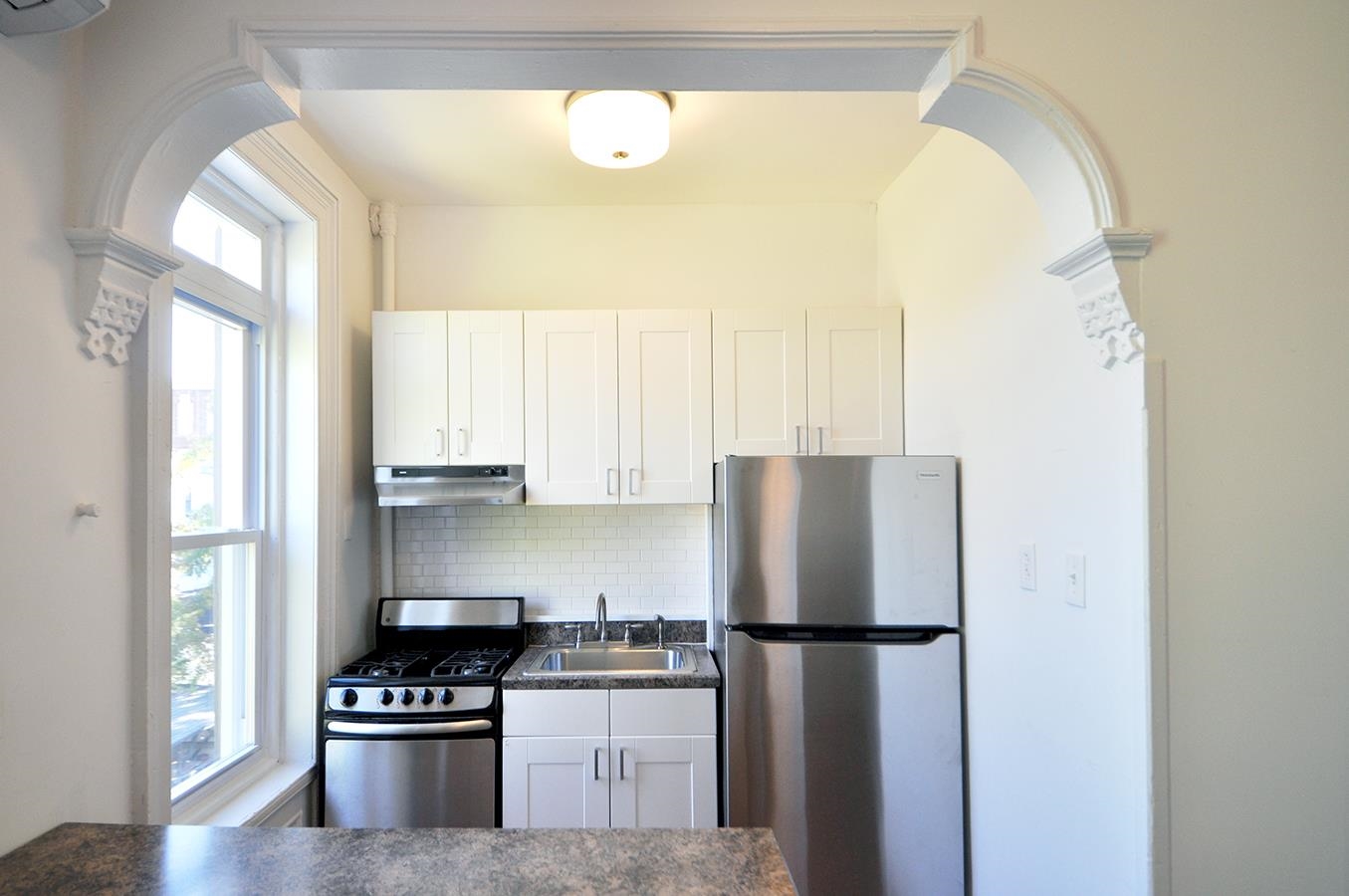 a kitchen with a refrigerator a stove and a window
