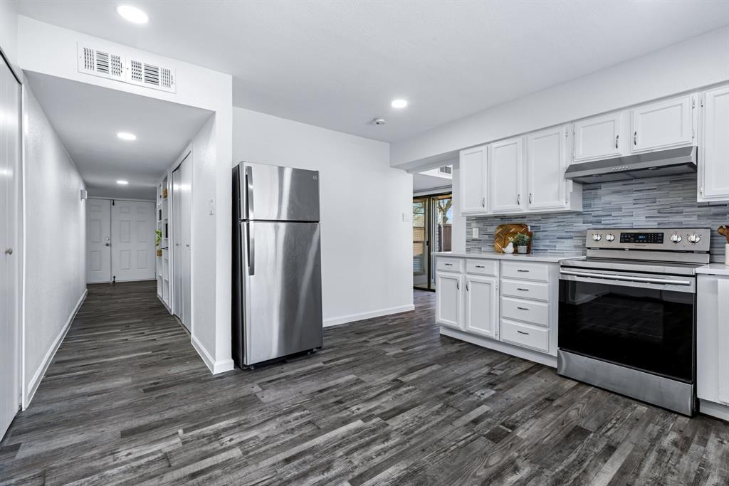 3429 Post Oak Road Garland, TX 75044 - Photo 23 of 36 a kitchen with stainless steel appliances a stove top oven a refrigerator and white cabinets with wooden floor