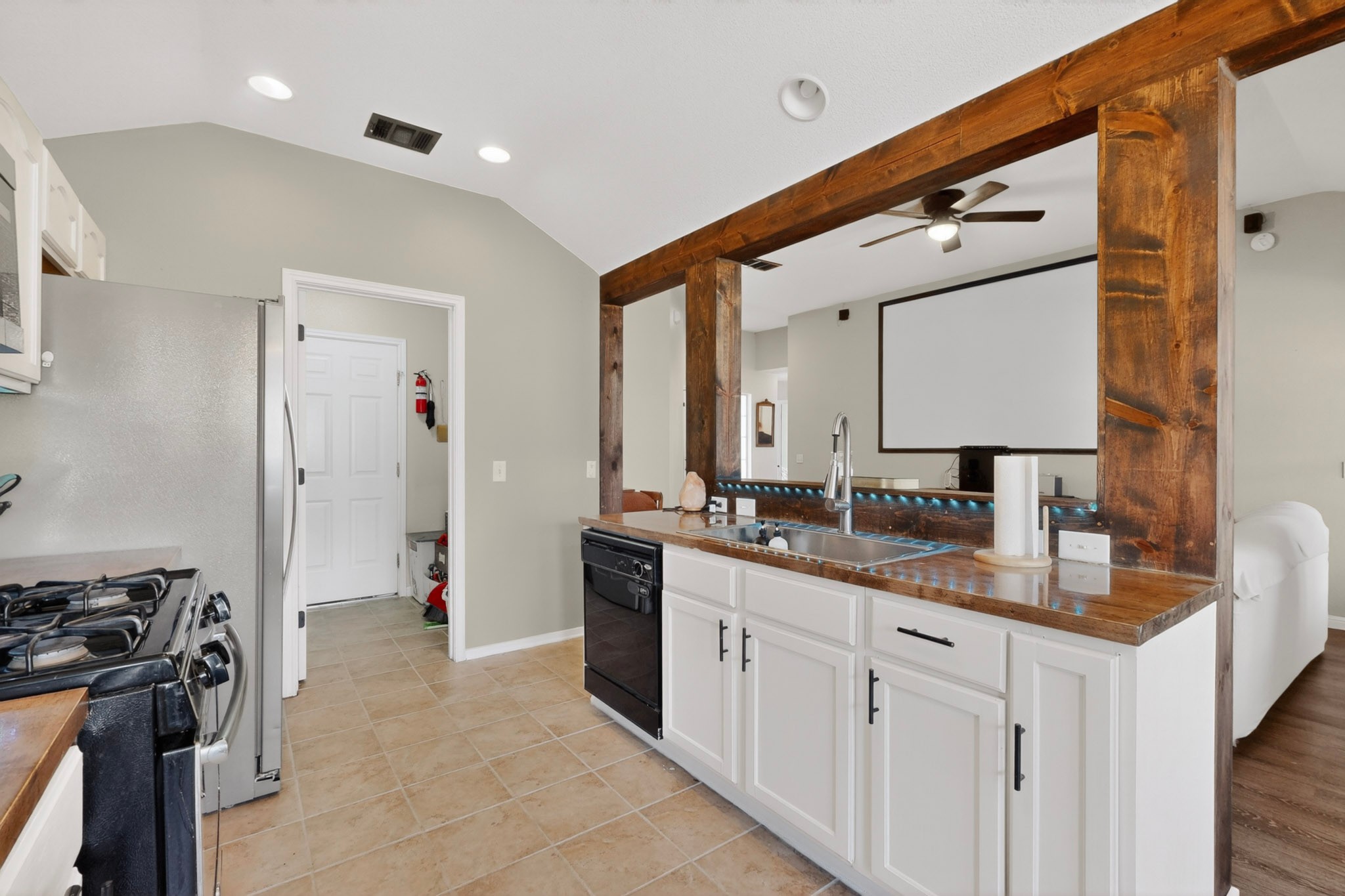 15104 Mimebark Way Austin, TX 78724 - Photo 12 of 38 Kitchen featuring white cabinetry with dark hardware, a stainless steel refrigerator, and a gas range
