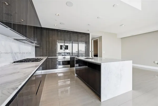 a kitchen with stainless steel appliances granite countertop a stove top oven a sink a dining table and chairs