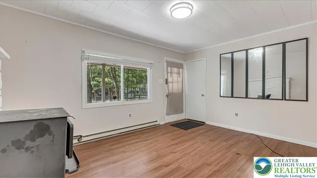a view of an empty room with wooden floor and a window