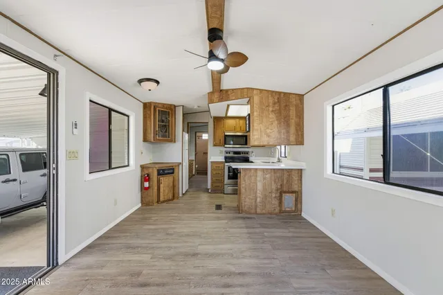 a kitchen with stainless steel appliances kitchen island granite countertop a stove a refrigerator a sink dishwasher with a dining table and chairs with wooden floor