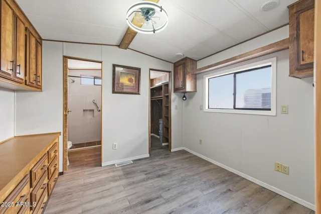 an empty room with wooden floor cabinet and windows