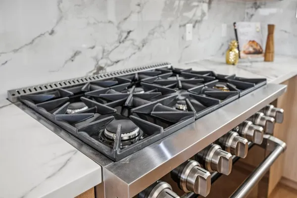 a kitchen with stainless steel appliances granite countertop a stove a sink dishwasher and white cabinets with wooden floor