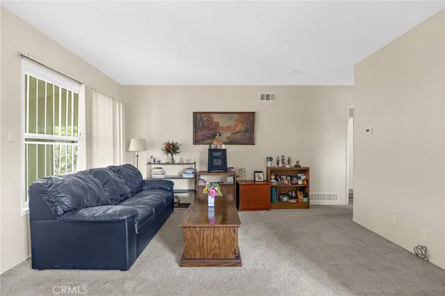 a living room with furniture kitchen view and a window