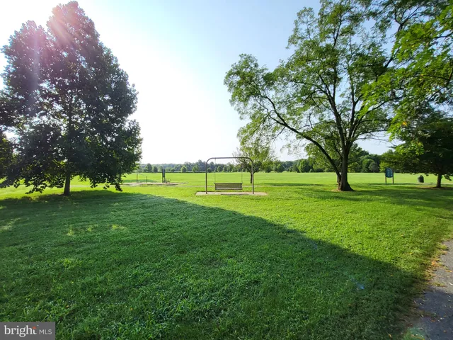 a view of grassy field with benches and trees all around