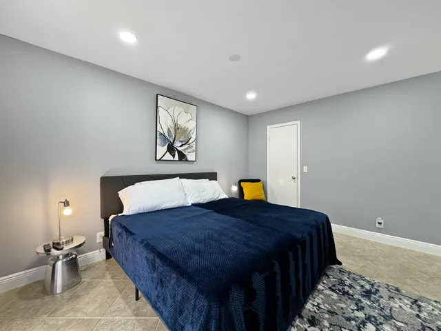 a bed sitting in a spacious bedroom next to a lamp
