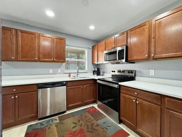 a kitchen with stainless steel appliances granite countertop wooden cabinets a stove top oven a sink and dishwasher
