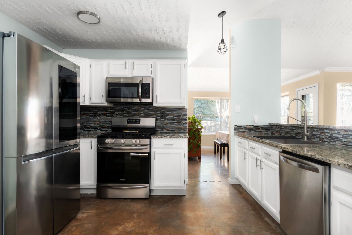 1412 Pigeon Forge Road Pflugerville, TX 78660 - Photo 8 of 20 a kitchen with stainless steel appliances granite countertop a stove a sink and a refrigerator