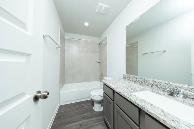 a bathroom with a granite countertop sink a toilet a mirror and shower