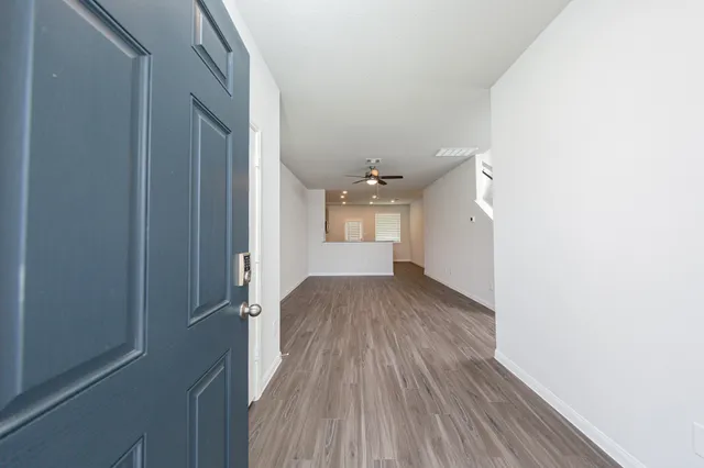 a view of a hallway with wooden floor and a kitchen