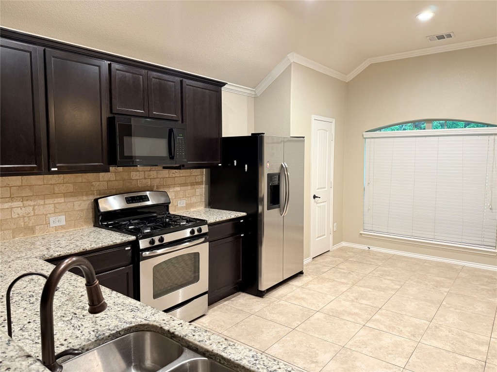 1704 Tranquility Lane Pflugerville, TX 78660 - Photo 13 of 19 a kitchen with granite countertop a stove a refrigerator and cabinets