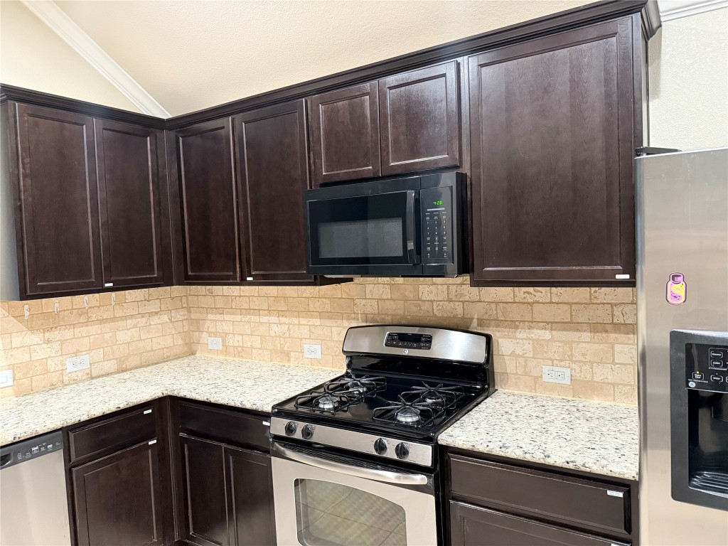 1704 Tranquility Lane Pflugerville, TX 78660 - Photo 18 of 19 a kitchen with granite countertop wooden cabinets and black stove top oven