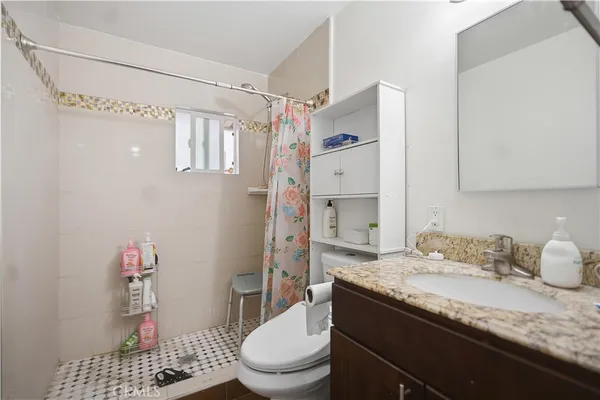 a bathroom with a granite countertop sink toilet and shower