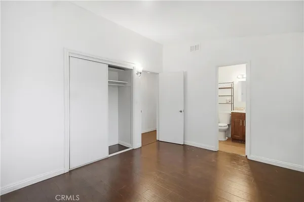 a view of an empty room with wooden floor and closet