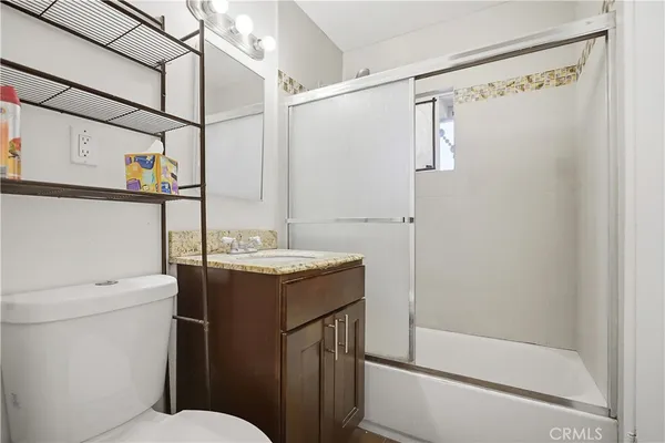 a bathroom with a granite countertop sink toilet and shower