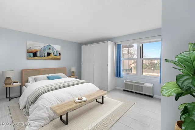 a bedroom with a bed a couch and potted plant next to a window