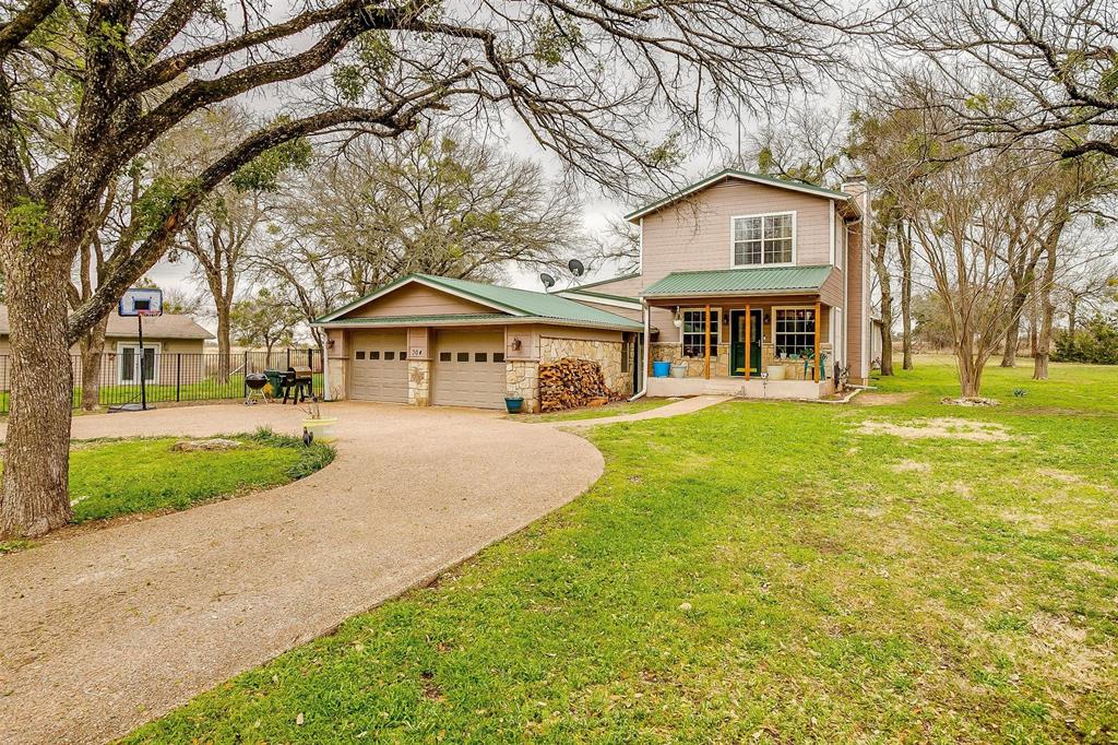 View of front facade featuring a garage, a front yard, and a porch