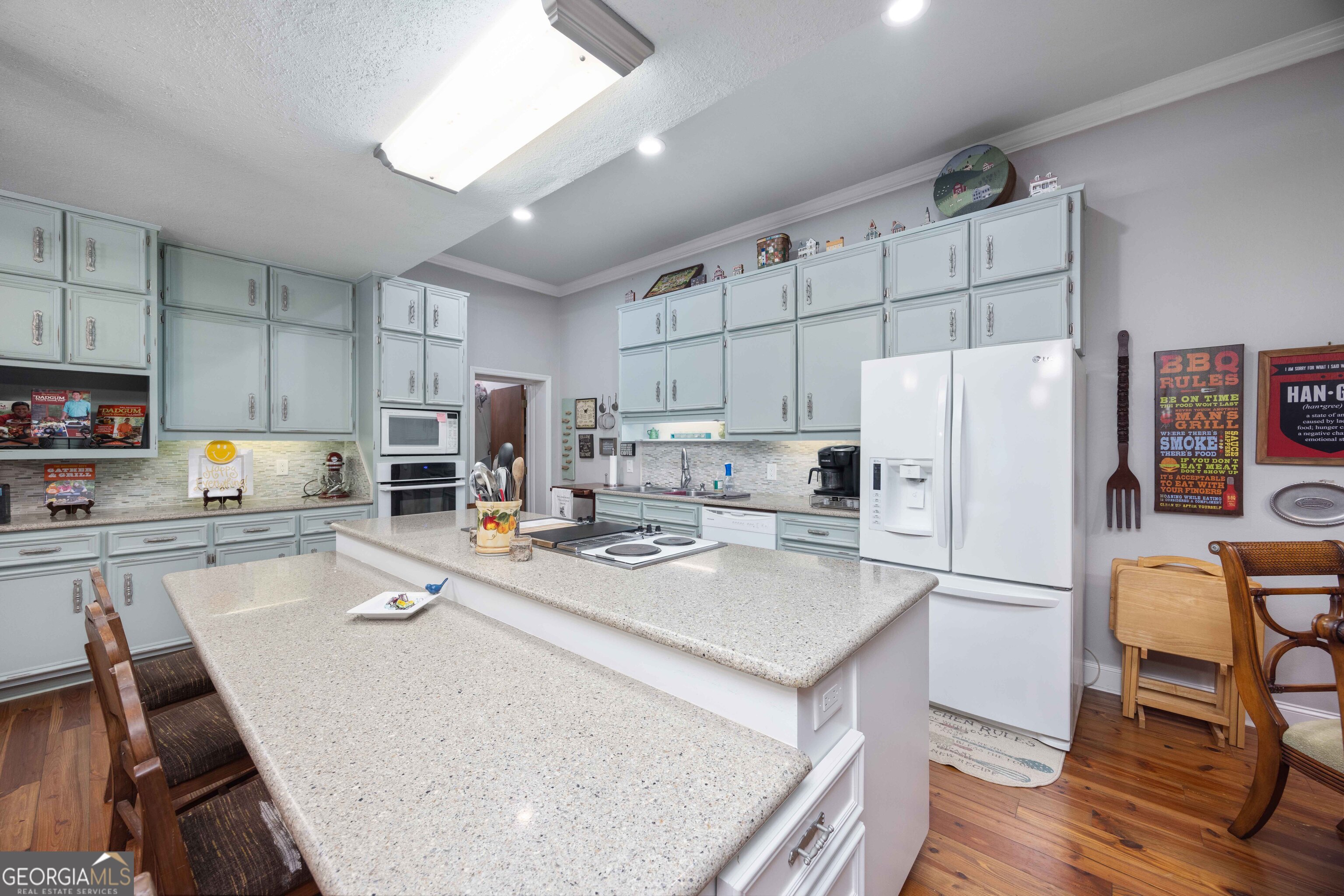 1132 Boat Club Road Hamilton, GA 31811 - Photo 23 of 50 a kitchen with a refrigerator a stove a microwave oven a sink dishwasher and white cabinets with wooden floor