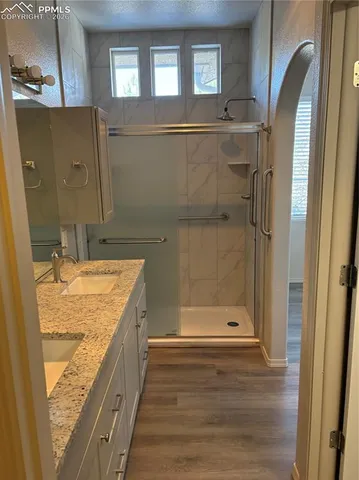a bathroom with a granite countertop sink a mirror and shower