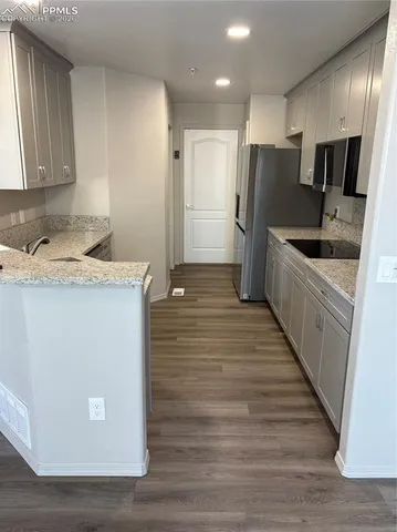 a kitchen with stainless steel appliances granite countertop a refrigerator a sink a stove and oven