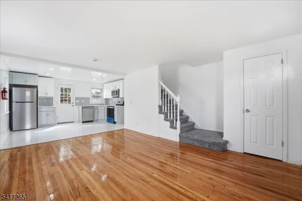 a view of empty room with wooden floor and kitchen