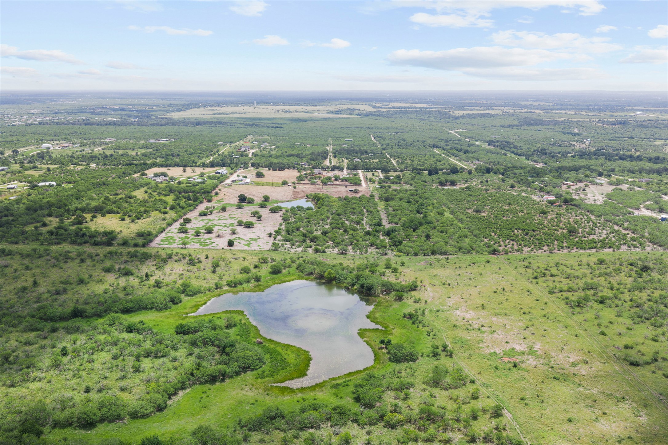 3315 Dry Creek Road Lockhart, TX 78644 - Photo 17 of 26 An aerial panorama reveals sprawling acreage with lush green fields and serene ponds, ready for development.