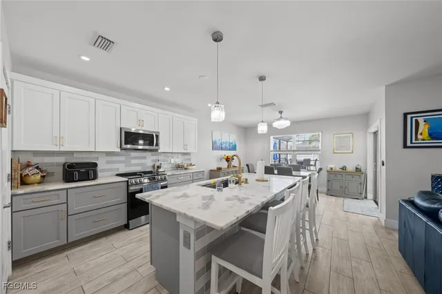 a kitchen with stainless steel appliances kitchen island granite countertop a stove a sink a dining table and chairs