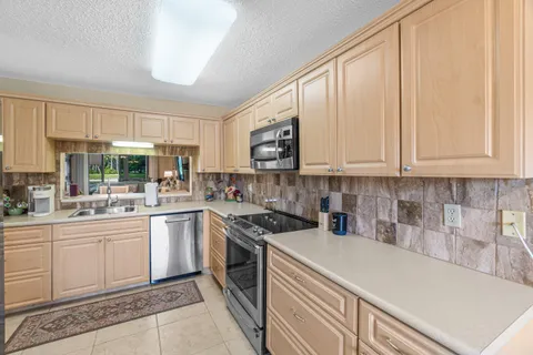 a kitchen with stainless steel appliances granite countertop a sink and cabinets with wooden floor