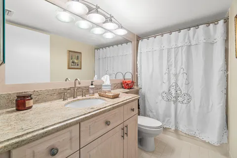 a bathroom with a granite countertop sink toilet and a mirror