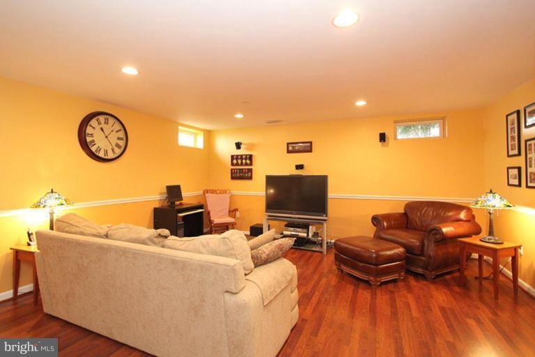 18409 Cornflower Road Boyds, MD 20841 - Photo 22 of 24 a living room with furniture a flat screen tv and a clock on the wall